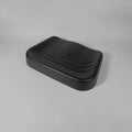 A black molded seat cushion with a contoured, wavy top surface and ribbed side edges, shown on a neutral gray studio background.